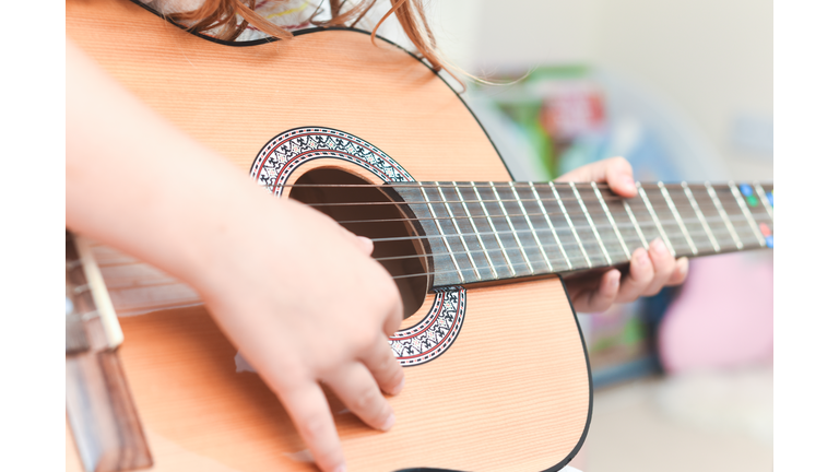 Girl learns to play guitar during a music lesson on the instrument