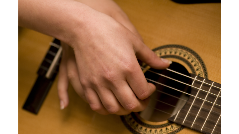 Two hands playing acoustic guitar