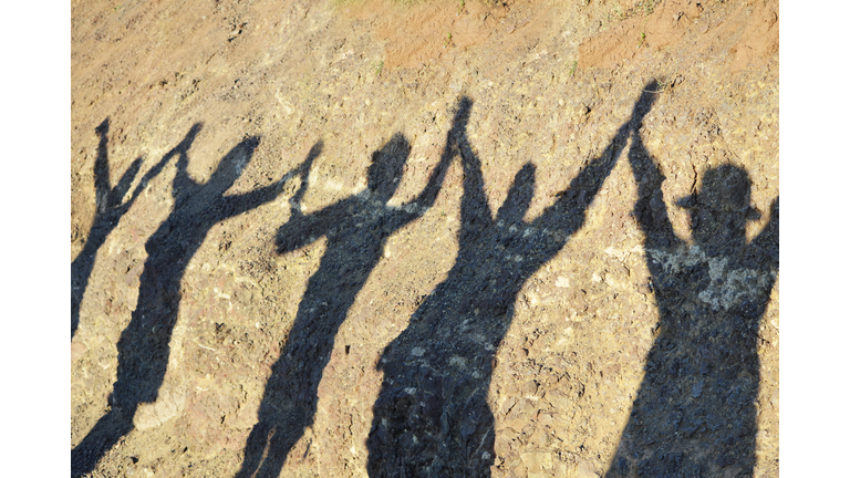 Unity and success and friendship concepts, shadow of group of women holding hands after finishing hiking in the mountain