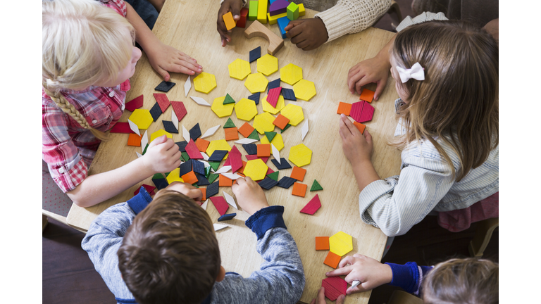 Children at preschool playing with colorful shapes