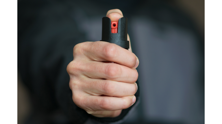 Man holding pepper spray (tear gas) in his hand. Self-defense. Blur background, close up