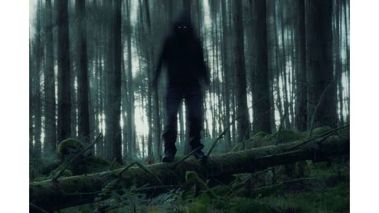 A horror concept of a figure with glowing eyes in a spooky forest. With a grunge, artistic edit.