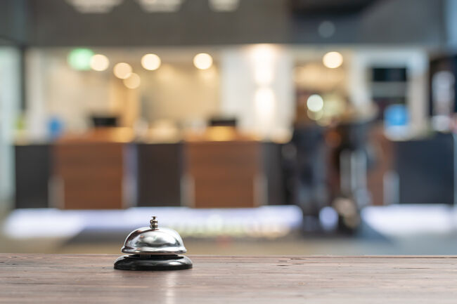 Hotel service bell on a table white glass and simulation hotel background. Concept hotel, travel, room