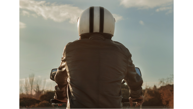 Rear View Of Man Riding Motorcycle Against Sky