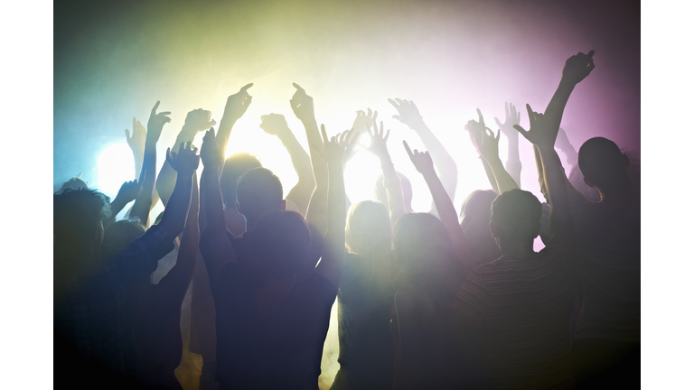 Crowd of people at concert waving arms in the air