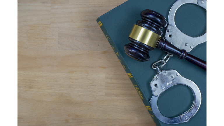 Gavel And Handcuffs On The Law Book Over The Wooden Table Background