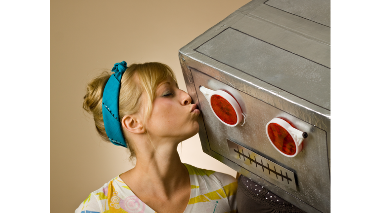 Close-up of woman in striped shirt kissing robot