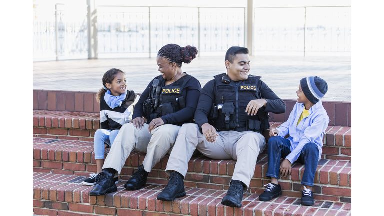 Two police officers in community, sitting with children