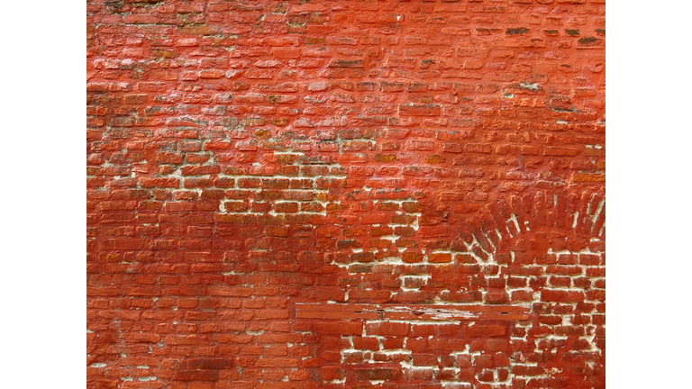 Weathered and decrepit red paint on an antique brick wall in Lille