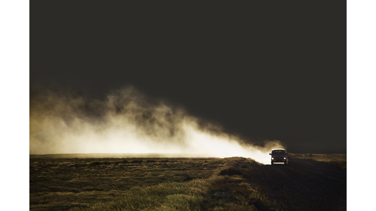 Van on dirt road creating dust