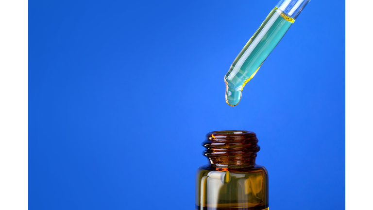 close up dropper with Cannabis CBD Oil used for medical purposes.marijuana CBD oil on blue background.