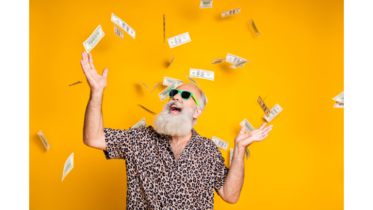 Portrait of crazy funky funny old bearded man hipster in green eyeglasses, eyewear look up at money falling scream great win lottery wear leopard stylish shirt isolated over yellow background