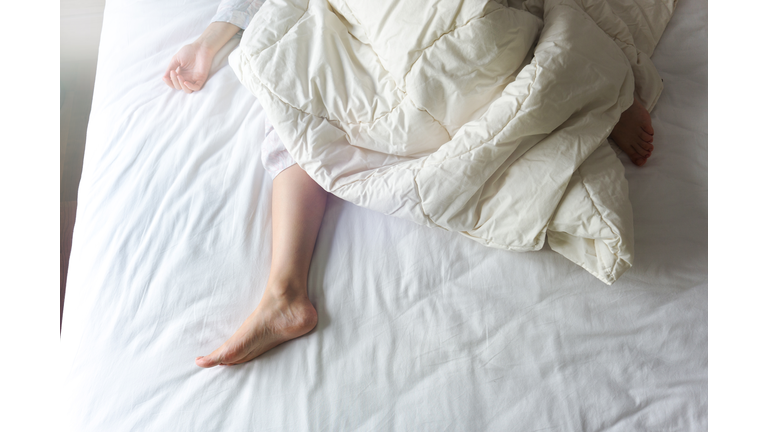 Bare Feet of a Young Woman on White Bed