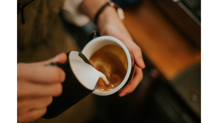 Close-up of barista hand while making frothy drink menu