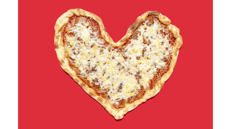 Heart shaped pizza margherita with pepperoni hearts on yellow background