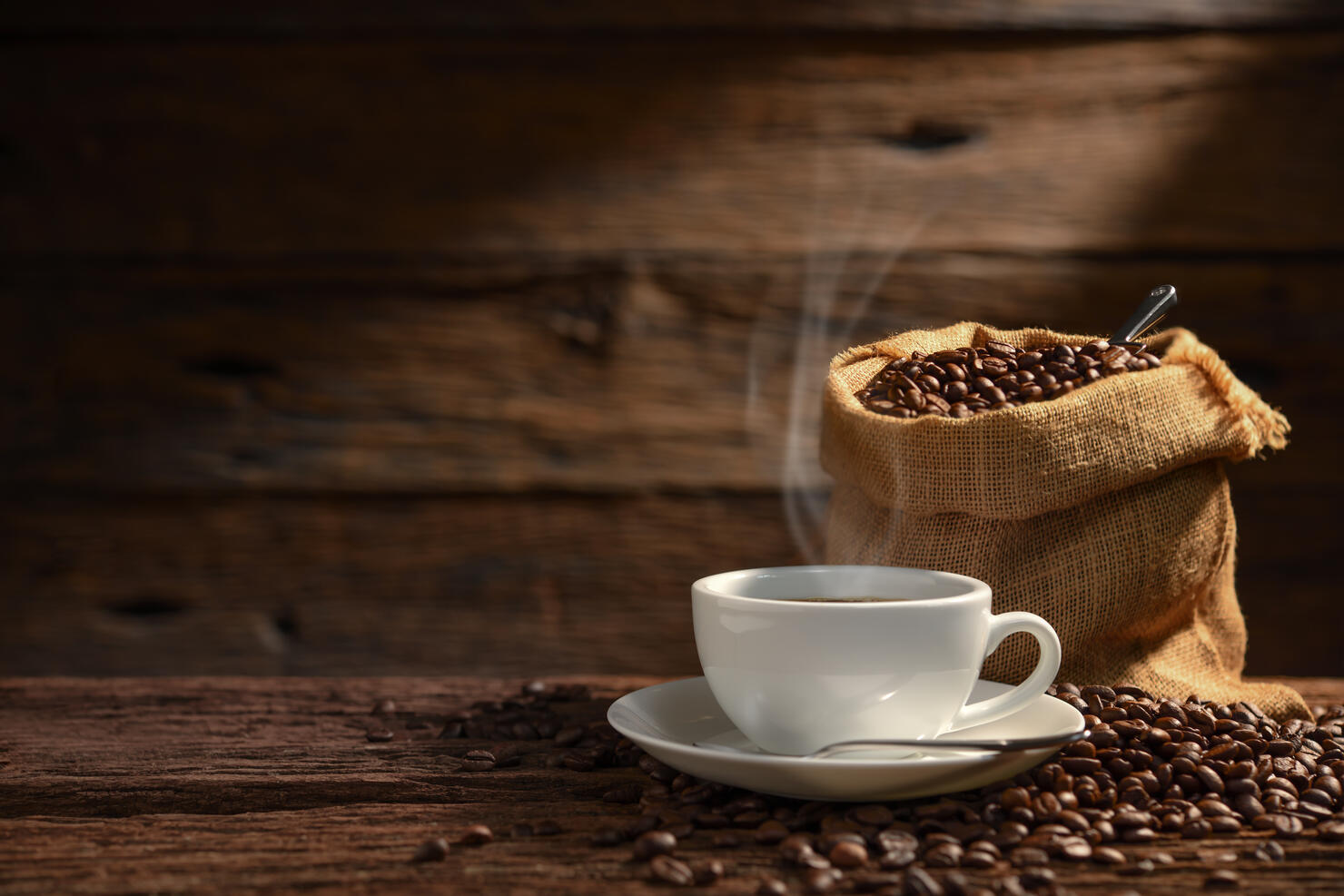 Cup of coffee with smoke and coffee beans on old wooden background