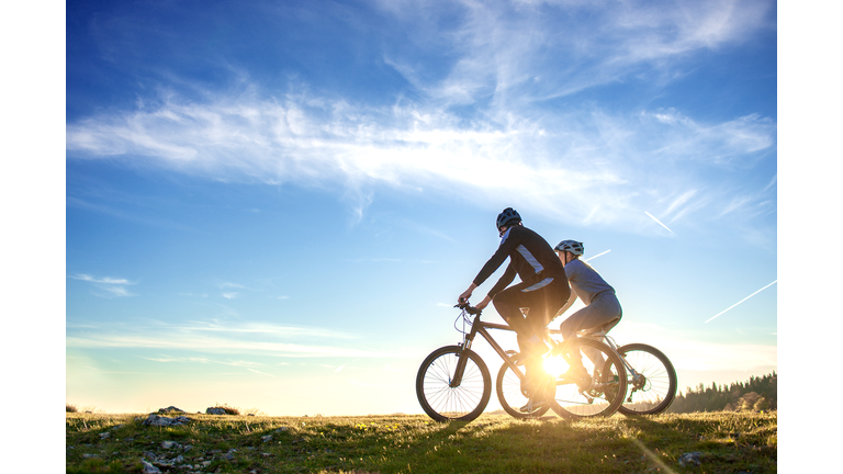 Happy mountain bike couple outdoors have fun together on a summer afternoon sunset