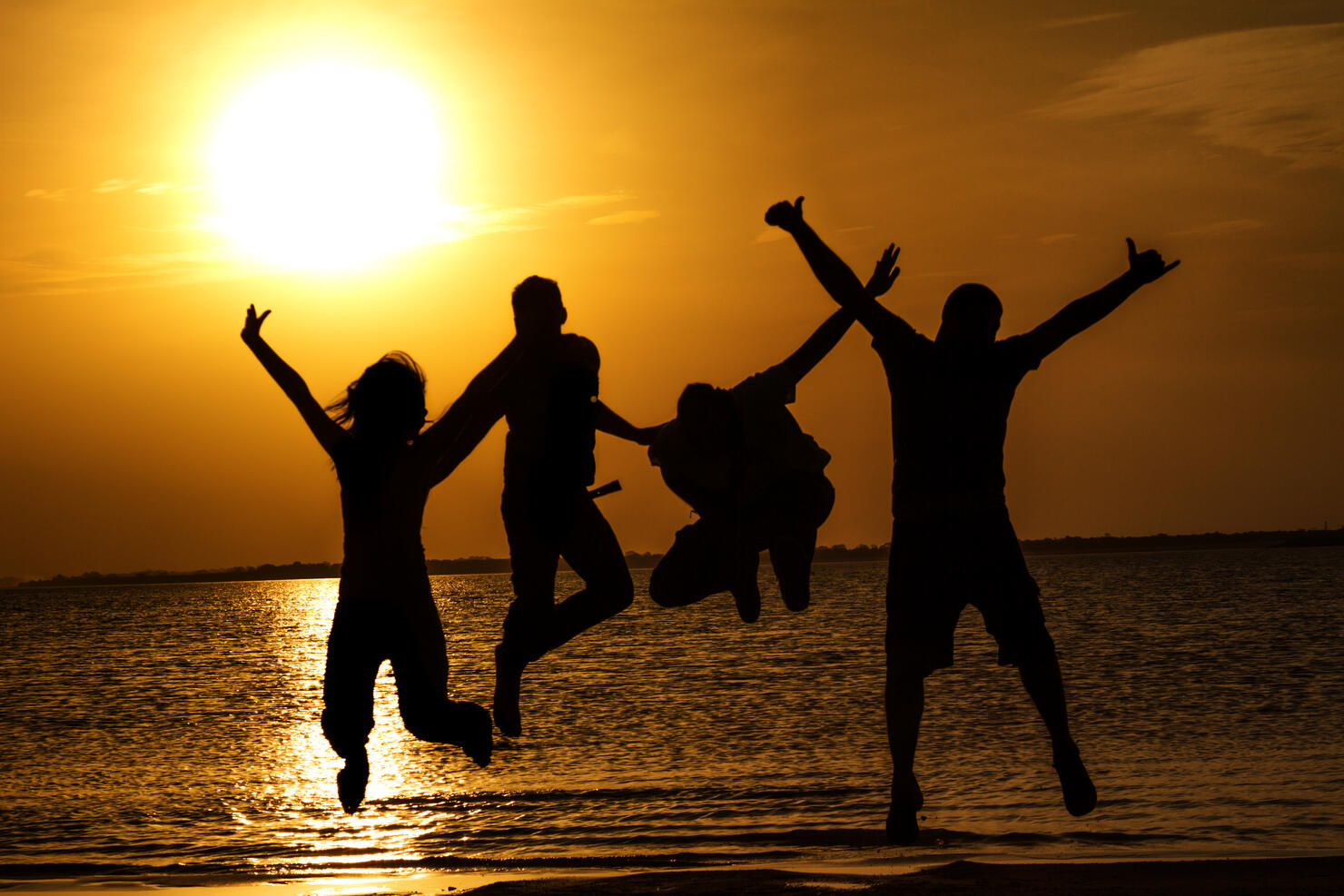 Spring break backlit group of young people jumping on beach