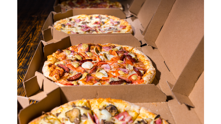 Close up of tasty pizzas with variety of toppings and cheese in cardboard take out boxes