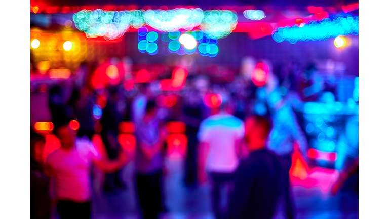 People dance sing have fun and relax in a nightclub blurred background. Flashes of light Beautiful blurry lights on the dance floor relax at night in the club