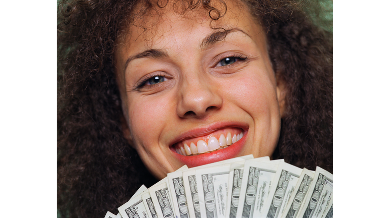 Young woman holding money, smiling, close up