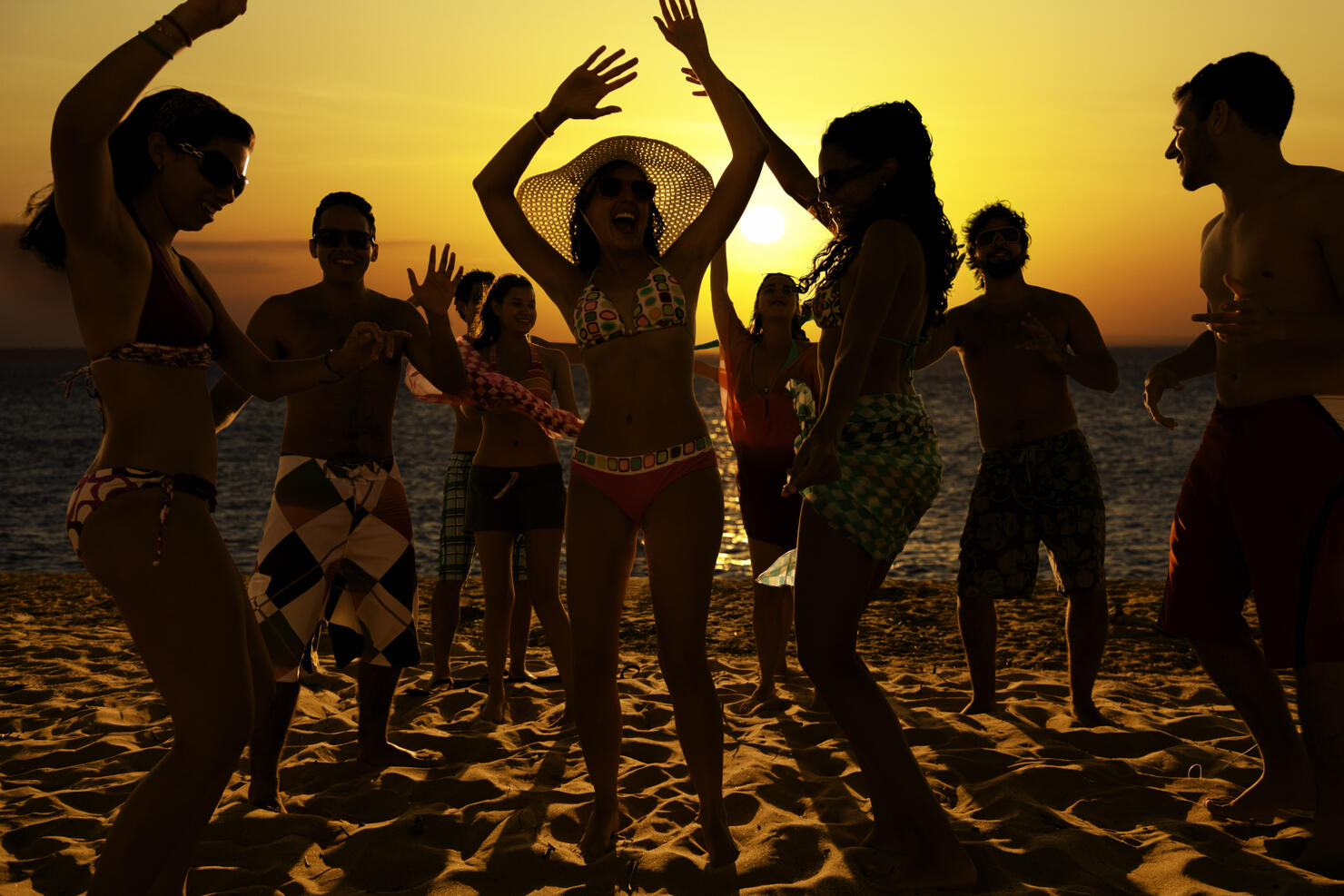 Spring break group of young people dancing on a beach