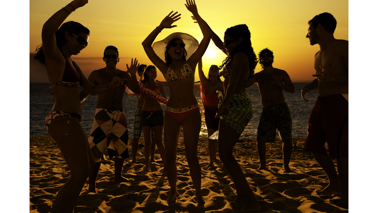 Spring break group of young people dancing on a beach