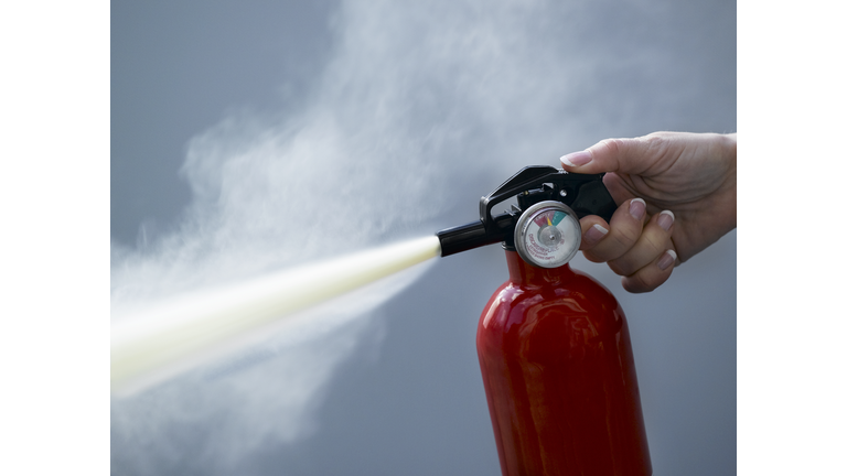 Woman using fire extinguisher, close-up