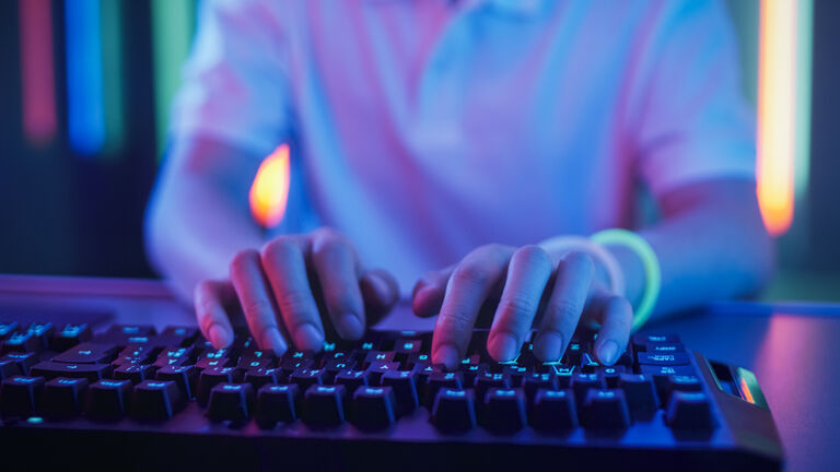 Close-up on the Hands of the Gamer Playing in the Video Game Using Keyboard. Hacker Breaks into System.
