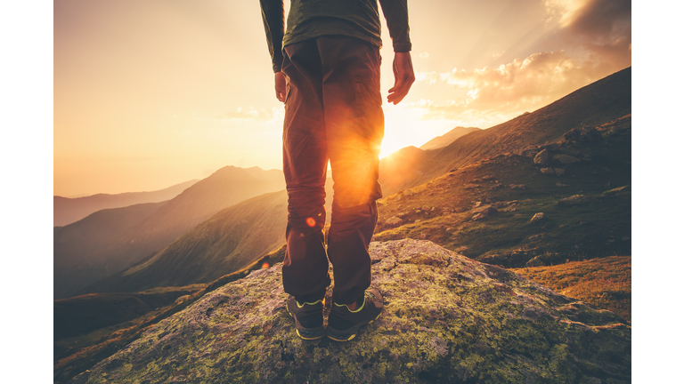 Young Man Traveler feet standing alone with sunset mountains