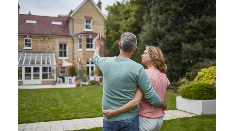 Mature couple standing in front of house