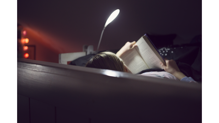 Child reading bedtime book lit by night light