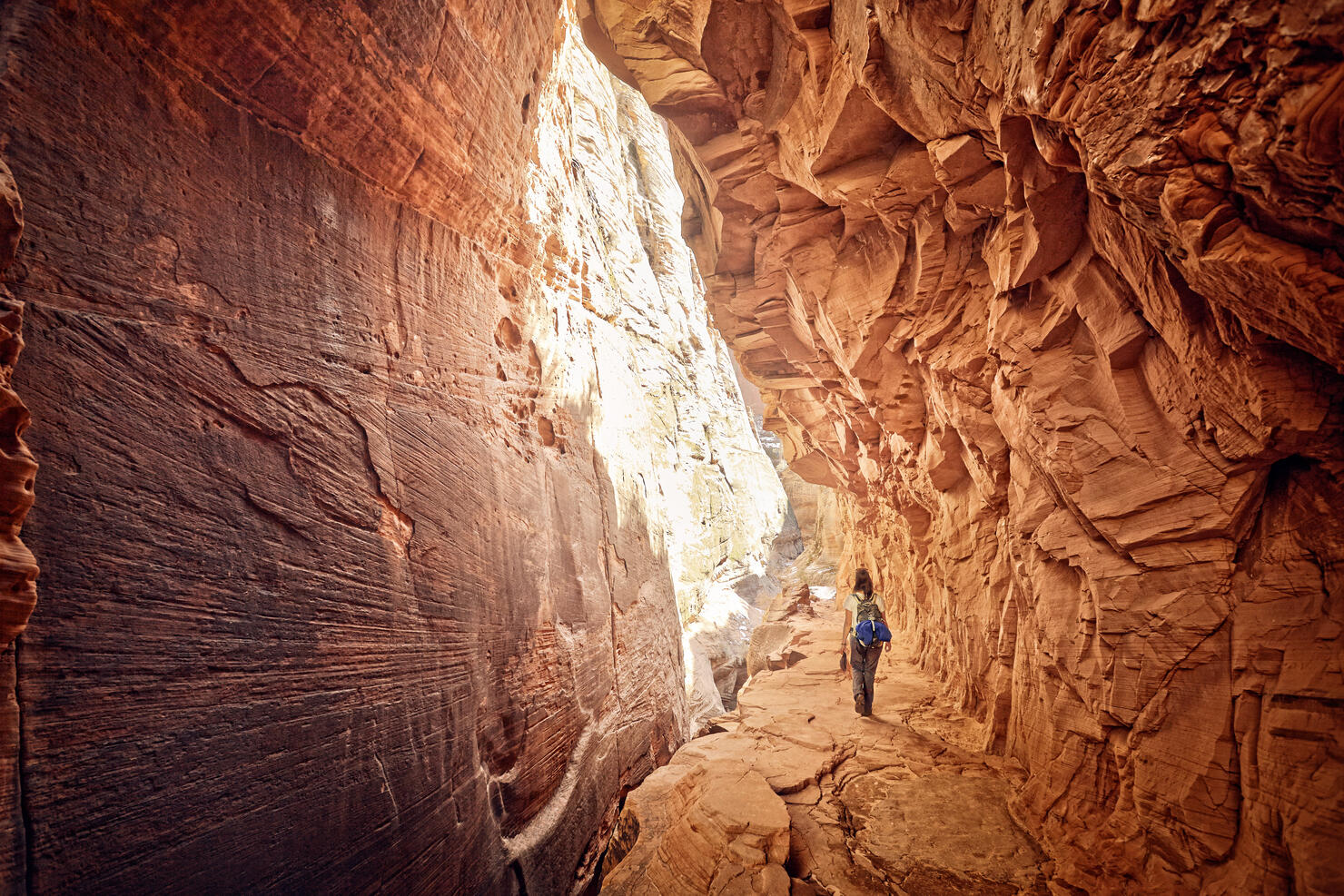 female hiker walking through red cave