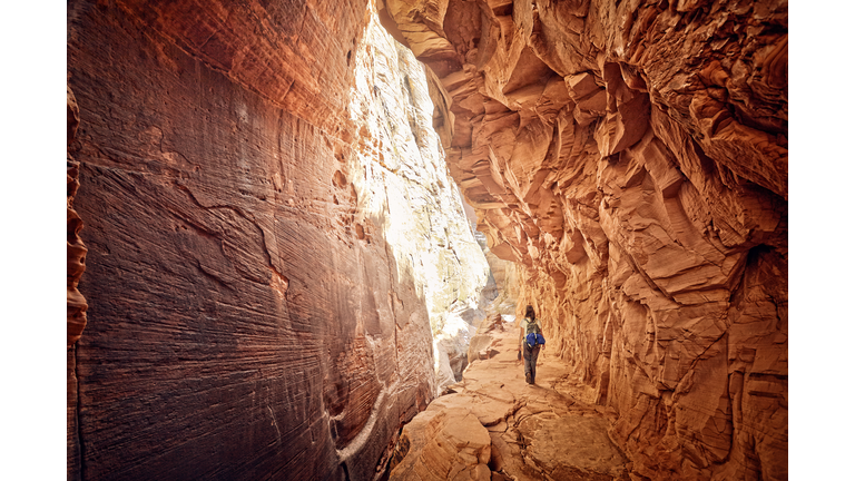 female hiker walking through red cave