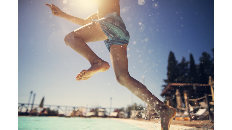 Little boy jumping into swimming pool