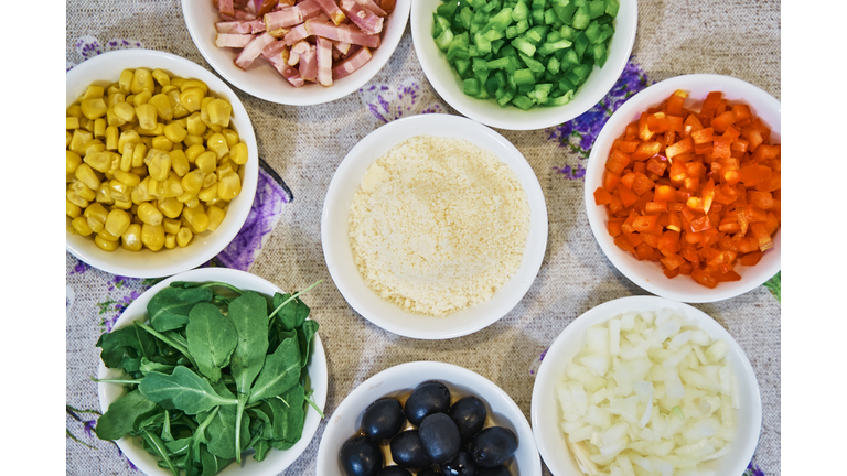 Flour bowl with green and red peppers, ham, corn and spinach around