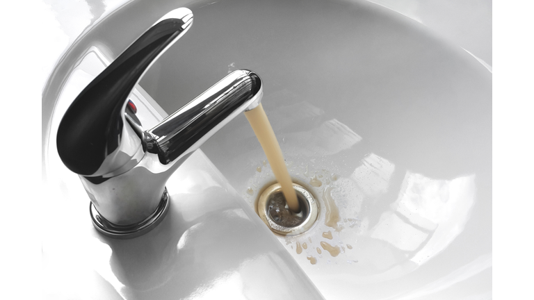 Water Tap With Running Dirty Muddy Water in a Sink