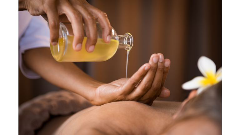 Therapist pouring massage oil at spa