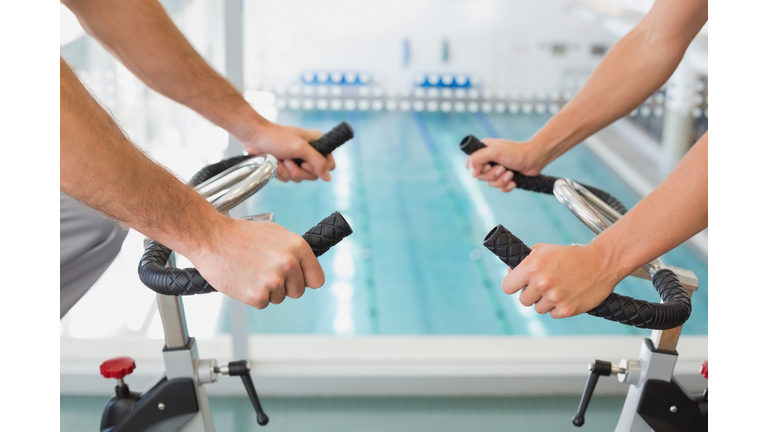 Mid section of couple working on exercise bikes at gym