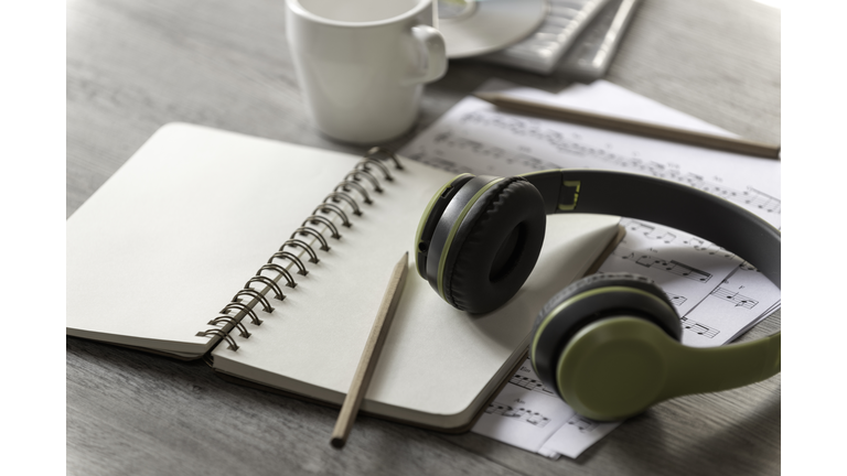 Paper notebook, pencil and earphone with note music paper on the table,Music writer concept, song writer,