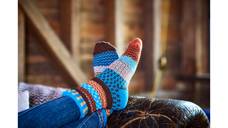 Person wearing patterned socks with feet up on leather sofa