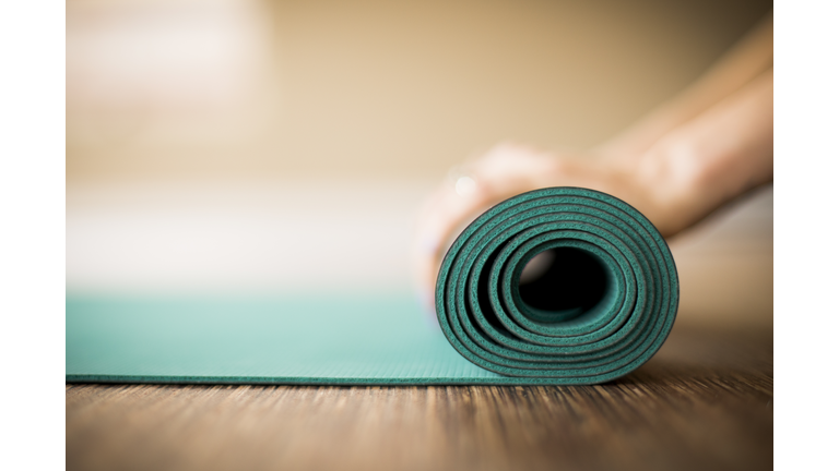 Woman rolling up yoga mat.