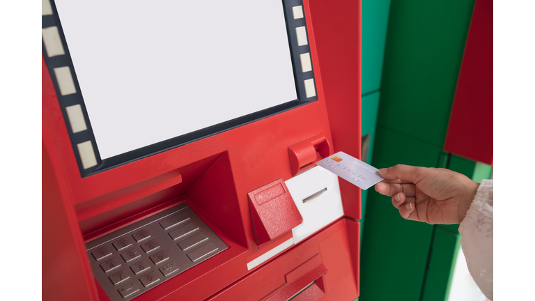 Young happy woman withdrawing money from credit card at ATM. Hand inserting ATM card into bank machine to withdraw money