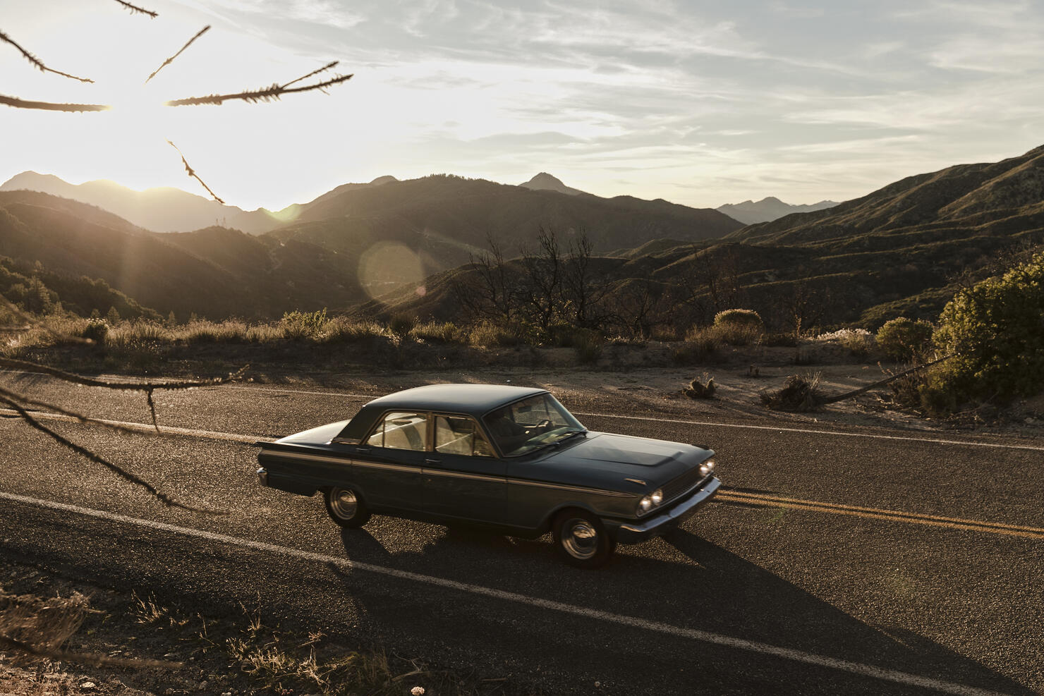 Young man driving vintage car on road trip in desert, Los Angeles, California, USA