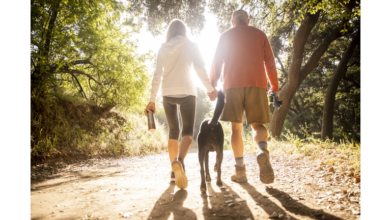 Active senior couple Walking with Dog on nature trail