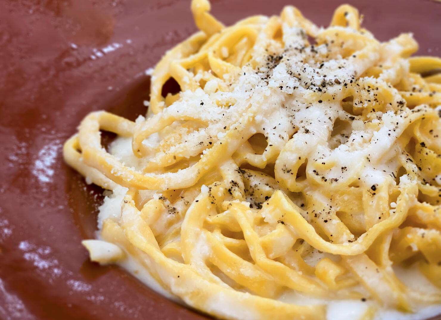 A portion of Italian traditional pasta with cacio e pepe - cheese and pepper- sauce