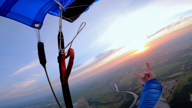 Point of view of a skydiver with his parachute at sunrise