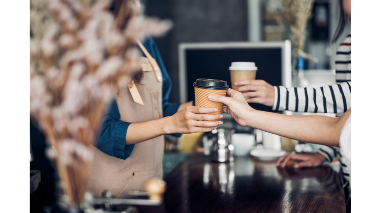 Barista served take away hot coffee cup to customer at counter bar in cafe restaurant,coffee shop business owner concept,Service mind waitress.