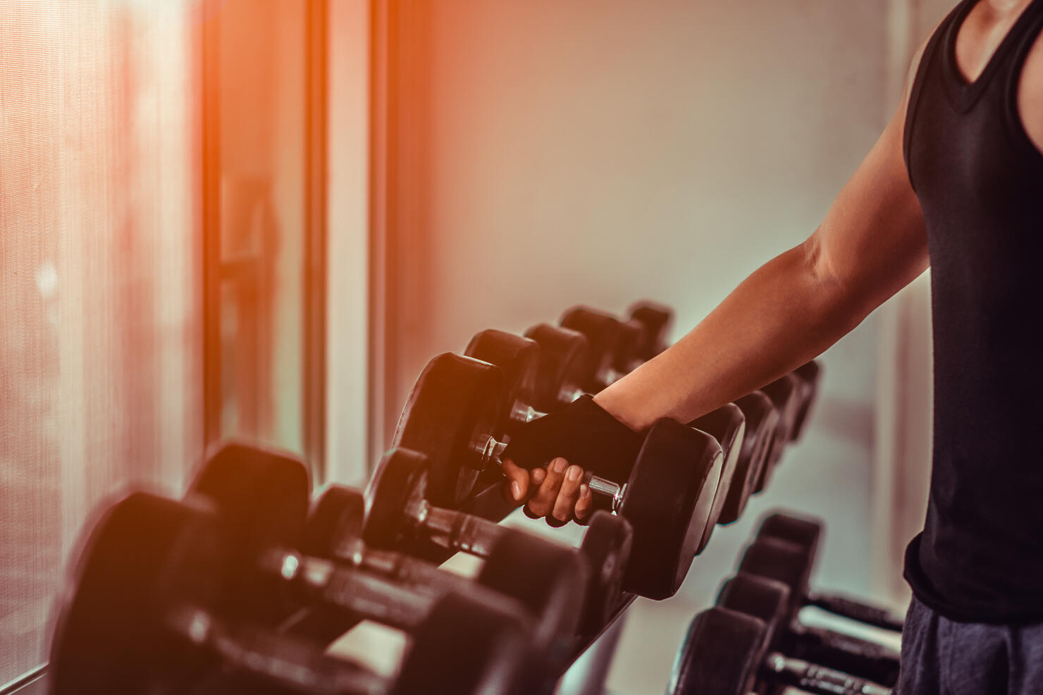 Close up many metal dumbbells on rack in gym.Athlete in the gym training with dumbbells. Hands with dumbbells.