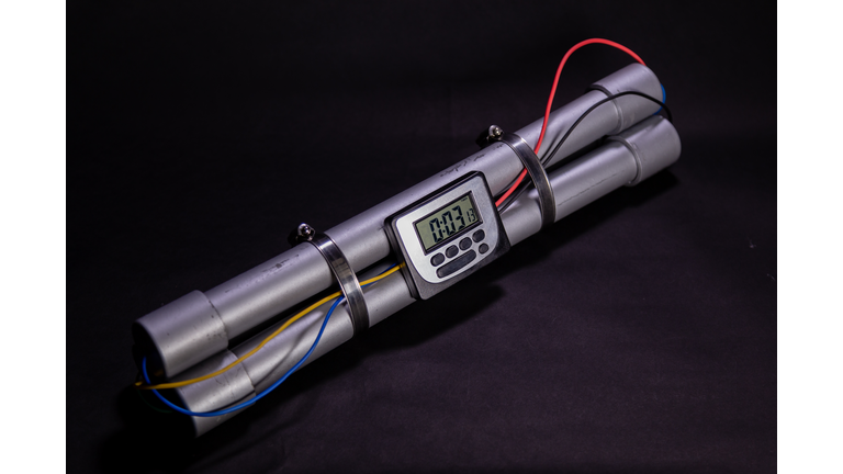 Pipe bomb with an clock timer to trigger detonation on black background